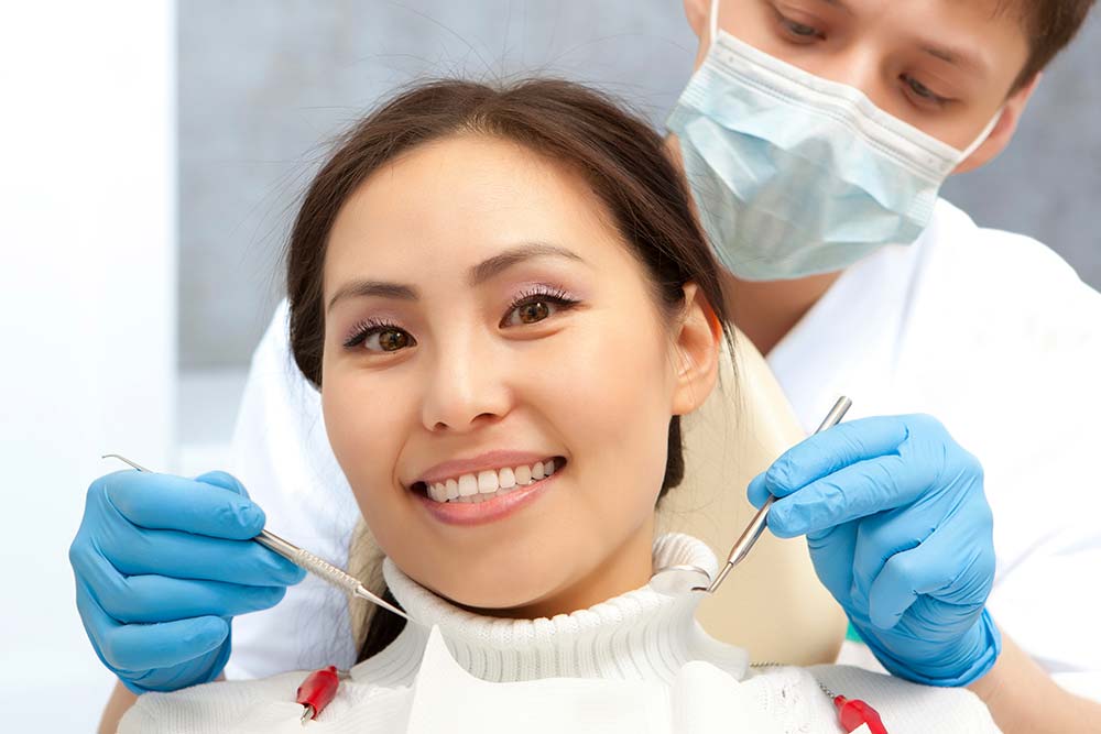 Patient Smiling While the Dentist Examine her Teeth